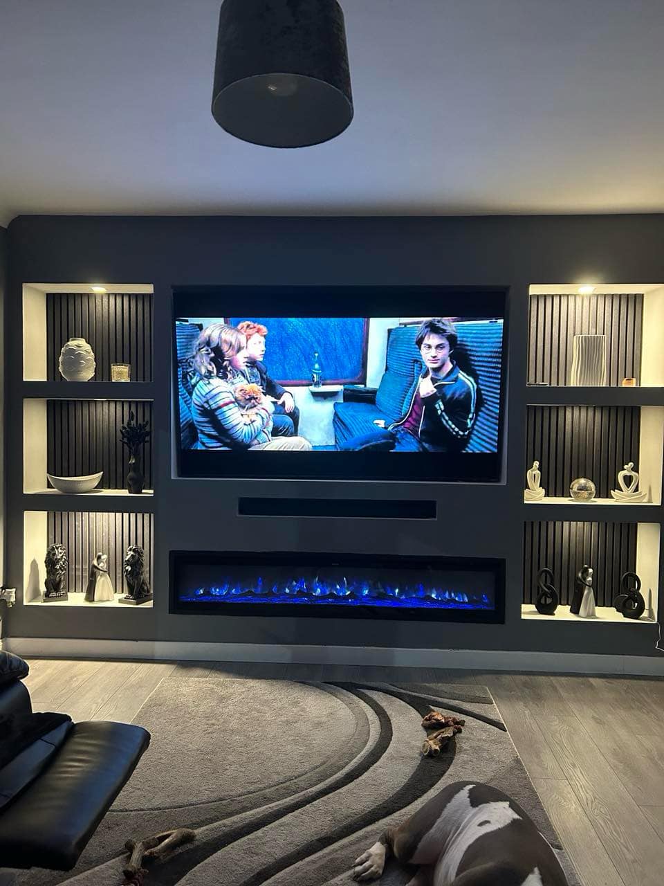 Black slat panel media wall with LED-lit shelving & panoramic electric fire media wall in Suffolk